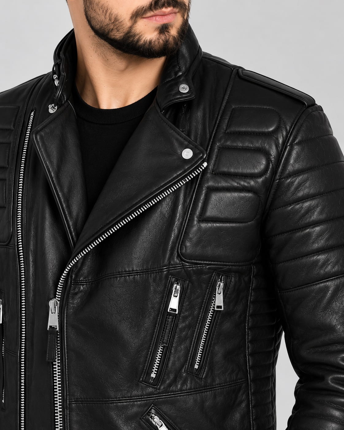 Close up detail of men black motorcycle leather jacket displaying padded chest panels, silver asymmetric zipper, snap lapel collar, and twin zip pockets.